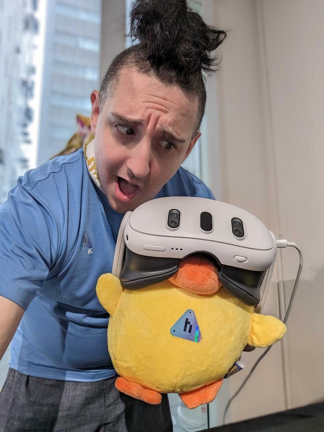 matt holding a fomo duck plushie wearing a vr headset